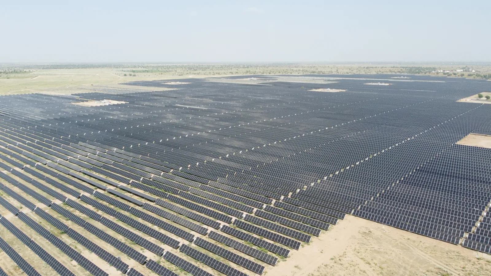 Aerial view of rows of solar panels stretching across desert land.