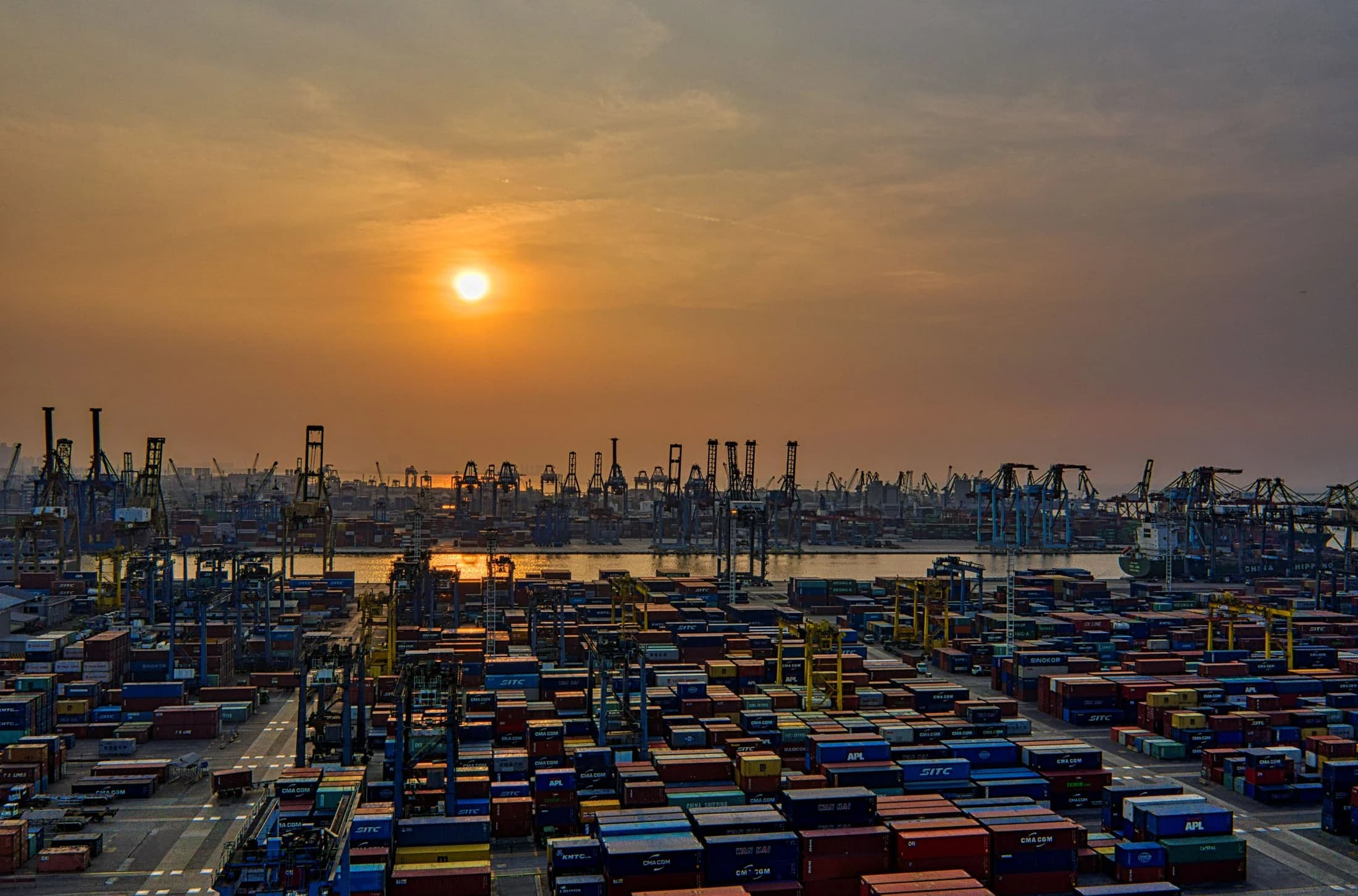 Container port cranes and vessels at sunset.