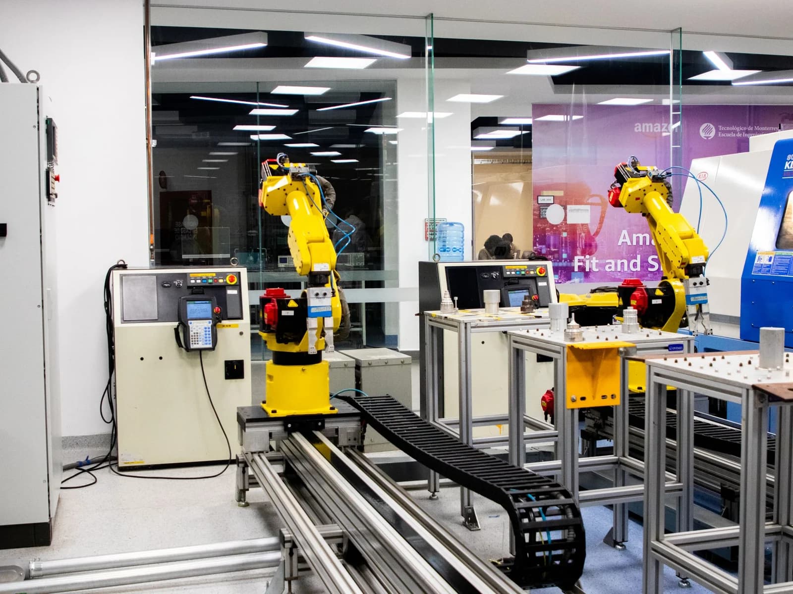 Yellow industrial robot arms inside a guarded automation cell.