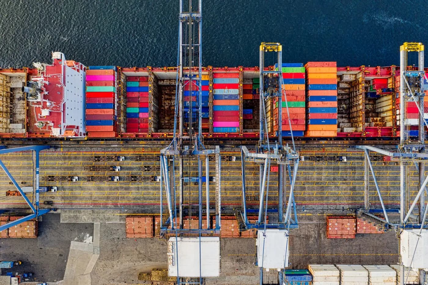 Container vessel alongside terminal gantry cranes, seen from above.